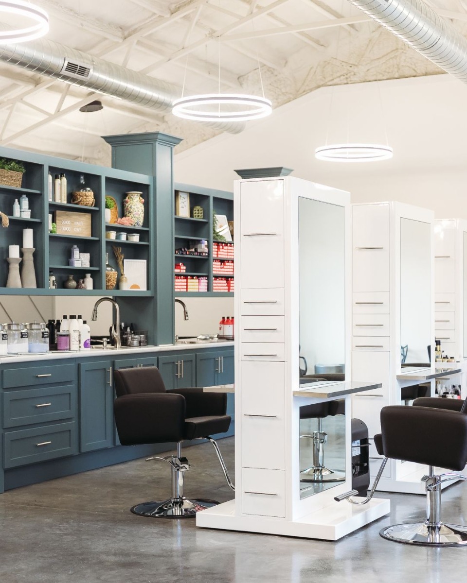 tall double-sided salon stations with full-length mirrors and built-in storage at use in a modern hair salon