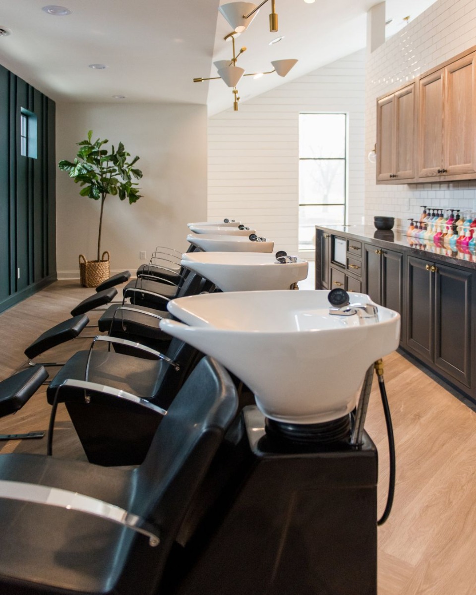 five shampoo bowls and chairs with ottomans in a large hair salon